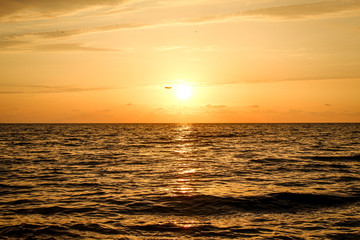 Golden, Fiery sunset on the Black Sea, on the beach. Coast, stones, waves, sun, beautiful sky, clouds. August, Batumi, Georgia. Water, ease, game. plane in the sky, tourism
