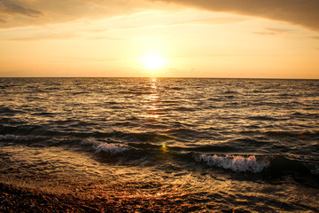 Obraz premium Golden, Fiery sunset on the Black Sea, on the beach. Coast, stones, waves, sun, beautiful sky, clouds. August, Batumi, Georgia. Water, ease, game.