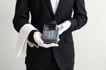 Waiter with payment terminal on light background