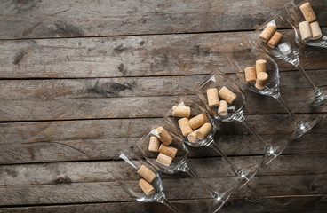 Wineglasses with corks on wooden background
