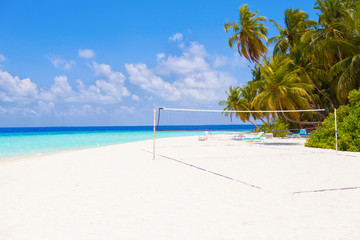 Fototapeta na wymiar Vacation summer sport holidays background wallpaper - sunny tropical Caribbean paradise beach with white sand on Maldives island Thailand style with palms and volleyball net sunbed