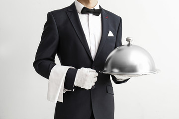 Waiter with tray and cloche on light background
