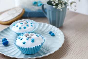 Plate with tasty Easter cupcakes on wooden table
