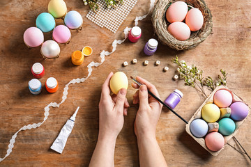 Woman painting Easter eggs at table