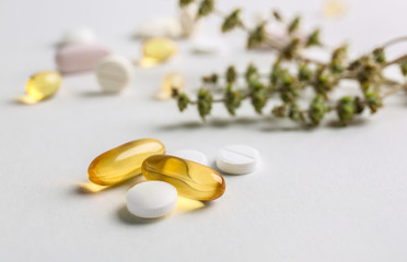 Different plant based pills on light background