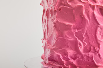 close up of pink cream on tasty baked birthday cake isolated on grey