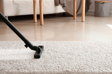 Brush of vacuum cleaner on carpet in room