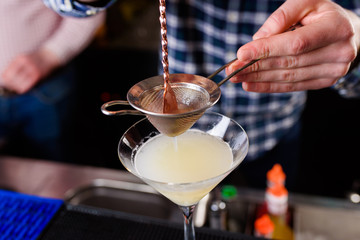 Expert barman is making cocktail at night club, Barman holds a cocktail in his hand. No face. Selective focus