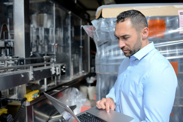 young man wine maker working filling wine bottle with automatic bottling machine