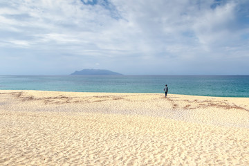 Fototapeta na wymiar Beautiful white sand beach on inakahama yakushima japan with a man stand alone