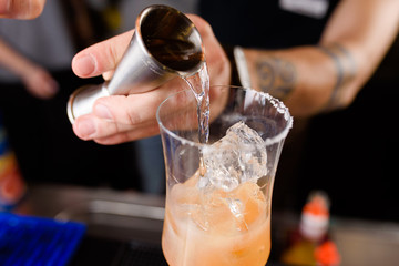 Expert barman is making cocktail at night club, Barman holds a cocktail in his hand. No face....