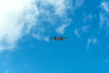 Fototapeta na wymiar Twin propeller aircraft flying in a blue sky with clouds