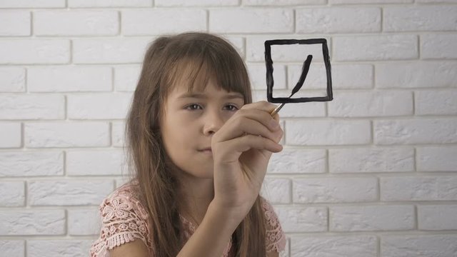 Selection. The little girl makes her choice, puts a tick in the box.
