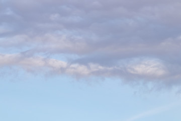 Spring evening sky background with white and grey cumulus clouds on warm sunset