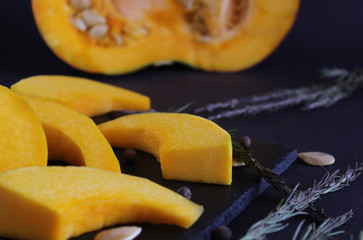 View directly on the pumpkin slices, which lies on a dark dish. Blur effect. Close-up.