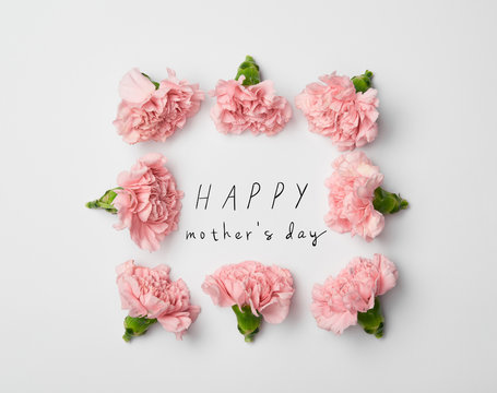 top view of floral frame made of pink carnations on white background with happy mothers day lettering
