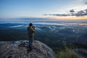 Silhouette man taking photo on top of a Mountain. 