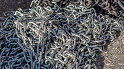 galvanized chain lies on the road under the rays of the Sun
