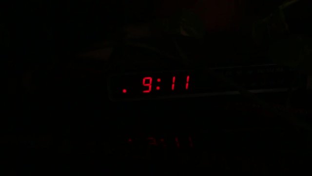 A digital clock flashing 9:11 in the darkness