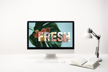 computer with fresh lettering and green leaf on monitor on desk on white background
