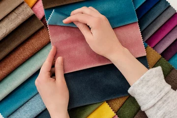 Zelfklevend Fotobehang Young woman with fabric samples for curtains at table. Multiple color fabric texture samples selection fabrics for interior decoration. Furniture upholstery © sevdastancheva