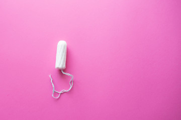 Menstrual cycle, feminine care, menstruation and intimate products concept with internal tampon isolated on pink background with copy space