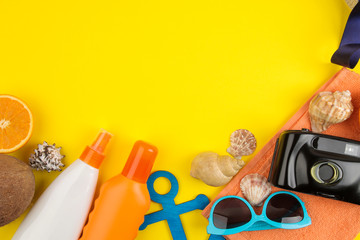 summer accessories with shells, flip flops, sun glasses, camera on a bright yellow background. top view. space for text