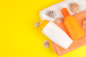 summer accessories. beach accessories. sunscreen and towels on a bright yellow background. top view. space for text