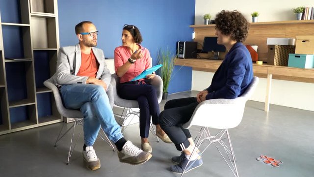 Business couple talking with young man during job interview at office