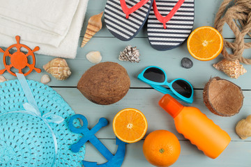 summer accessories. beach accessories. sunscreens, a hat, shells, and sunglasses on a blue wooden table. top view.