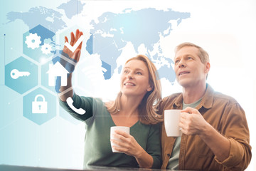 amused couple holding coffee cups, smart home concept