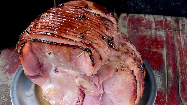 pouring syrup glaze over baked spiral cut ham