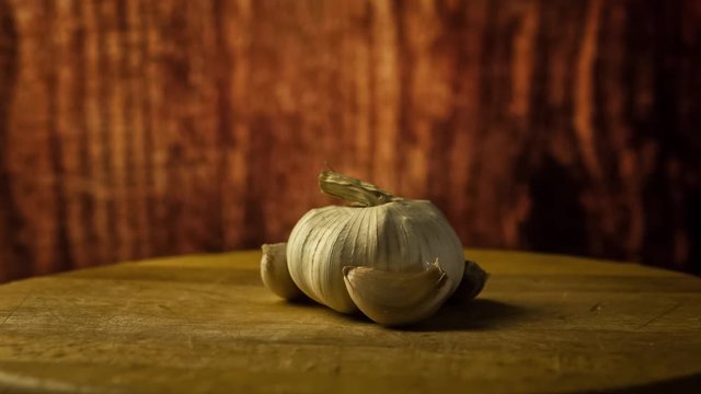 Head of garlic and cloves of garlic on wodden desk. Rotating, turntable shot. Still life