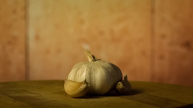 Head of garlic and cloves of garlic on wodden desk. Rotating, turntable shot. Still life