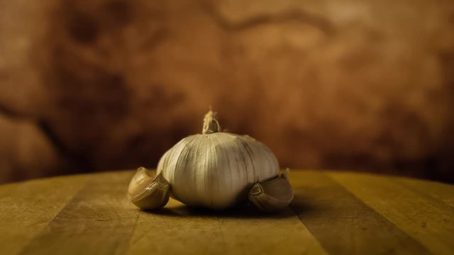 Head of garlic and cloves of garlic on wodden desk. Rotating, turntable shot. Still life