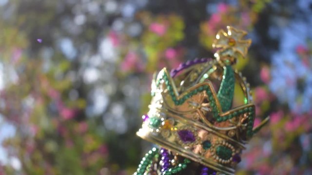 Outdoor Mardi Gras beads and crown on light post in sunshine