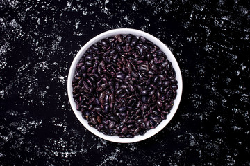 Black beans on a white plate on a dark background