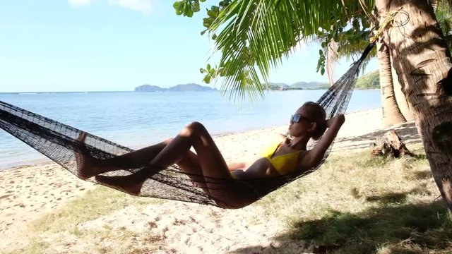Young asian girl, relaxes in a hammock on the beach.