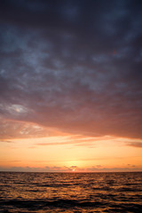 Obraz premium Golden, Fiery sunset on the Black Sea, on the beach. Coast, stones, waves, sun, beautiful sky, clouds. August, Batumi, Georgia. Water, lightness, play. Pink, lilac, crimson