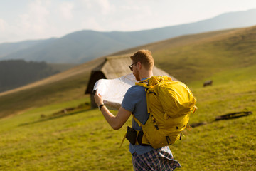 Young redhair man on mountain hiking holding a map
