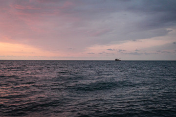 Naklejka premium Golden, Fiery sunset on the Black Sea, on the beach. Coast, stones, waves, sun, beautiful sky, clouds. August, Batumi, Georgia. Boat, ship. Water, lightness, play. Pink, lilac, crimson