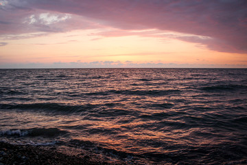 Golden, Fiery sunset on the Black Sea, on the beach. Coast, stones, waves, sun, beautiful sky, clouds. August, Batumi, Georgia. Water, lightness, play. Pink, lilac, crimson
