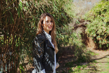 Young smiling blonde woman wearing a leather jacket in the park