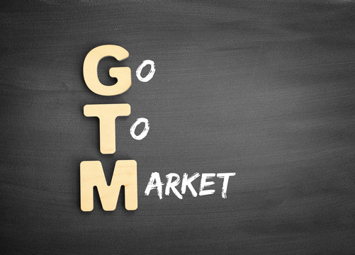 Wooden alphabets building the word GTM - Go To Market acronym on blackboard