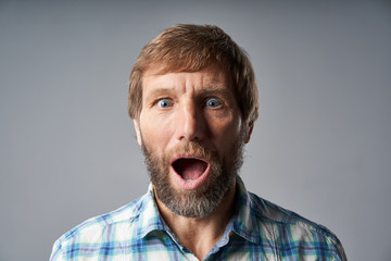 Surprised mature man in checkered shirt with mouth opened