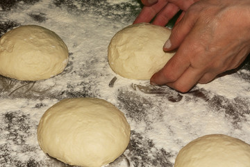 Traditional Caucasian cuisine. Elderly woman cooks dough for the Ossetian pies. Preparing dough stretching ball kneading. Close up. Selective focus.