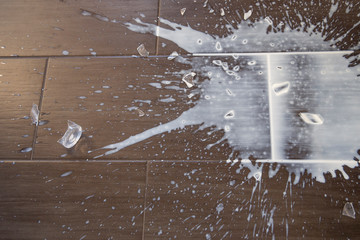 Top view on split milk and broken  glass on dark floor