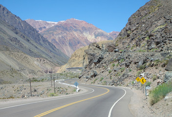 Scenic view of winding road. Empty road. Warning signs. Andes or Andean Mountains. Argentina, Mendoza Province, near to the border with Chile