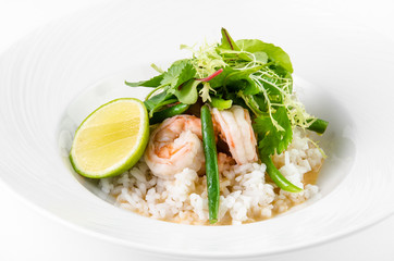 Prawns in coconut curry teriyaki, string beans and lime on a plate on a white background