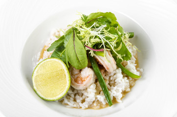 Prawns in coconut curry teriyaki, string beans and lime on a plate on a white background
